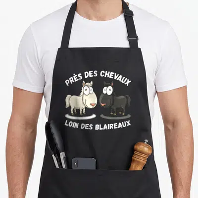 Tablier de cuisine noir avec deux poneys dessinés et le texte près des chevaux loin des blaireaux imprimé en blanc.