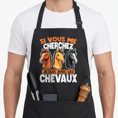 Tablier de cuisine noir avec trois têtes de chevaux et le texte Si Vous Me Cherchez Je Suis Avec Les Chevaux en orange et blanc.