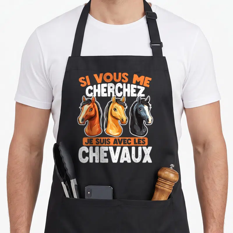 Tablier de cuisine noir avec trois têtes de chevaux et le texte Si Vous Me Cherchez Je Suis Avec Les Chevaux en orange et blanc.