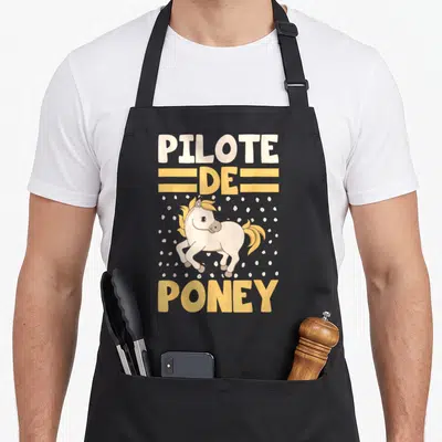 Tablier de cuisine noir avec illustration d'un poney blanc et texte Pilote de Poney en lettres jaunes et crème.