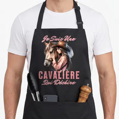 Tablier de cuisine noir avec une illustration d'une cavalière en chapeau caressant un cheval et du texte rose.