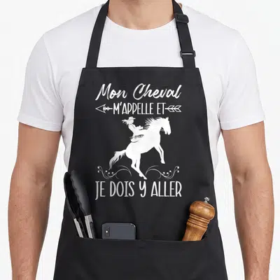 Tablier de cuisine noir avec une silhouette blanche de cavalière, des flèches et le texte Mon Cheval M'Appelle et Je Dois Y Aller.