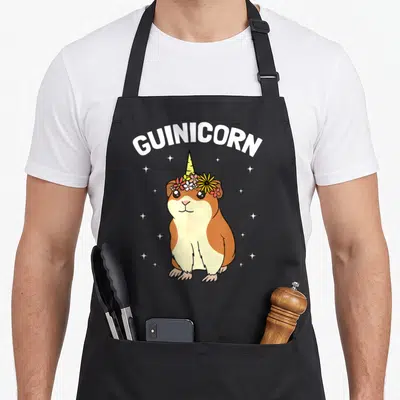 Tablier de cuisine noir avec illustration d'un guinicorn aux couleurs vives et étoiles scintillantes.