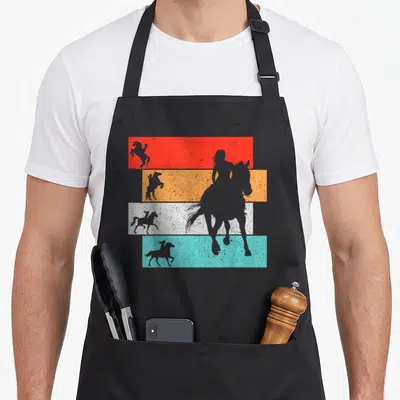 Tablier de cuisine noir avec silhouettes de chevaux et cavalières sur bandes orange, blanche et turquoise texturées.