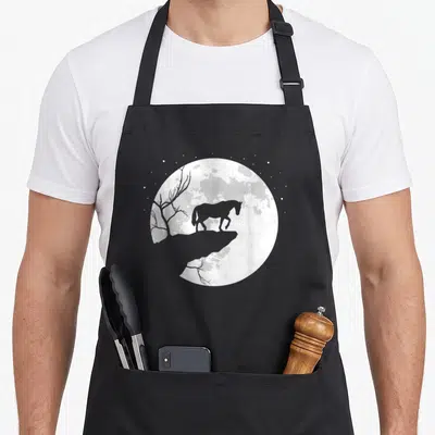 Tablier de cuisine noir avec silhouette de cheval devant une lune et un arbre sec.