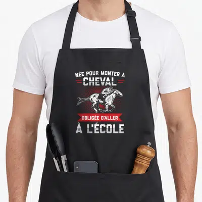 Tablier de cuisine noir avec inscription née pour monter à cheval et illustration de cavalier en action.