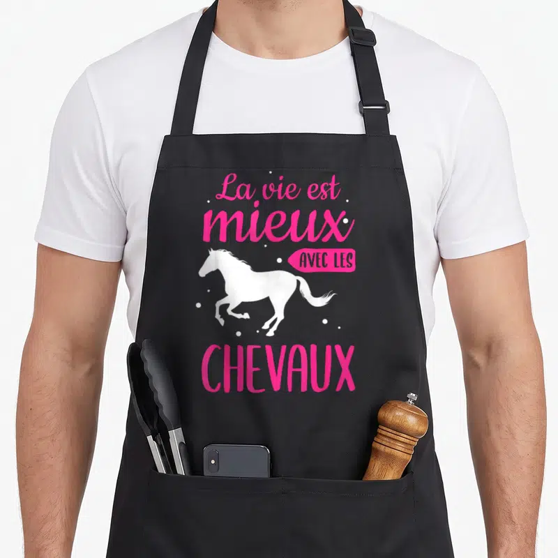 Tablier de cuisine noir avec une silhouette de poulain blanc et le texte La vie est mieux avec les chevaux en rose vif.