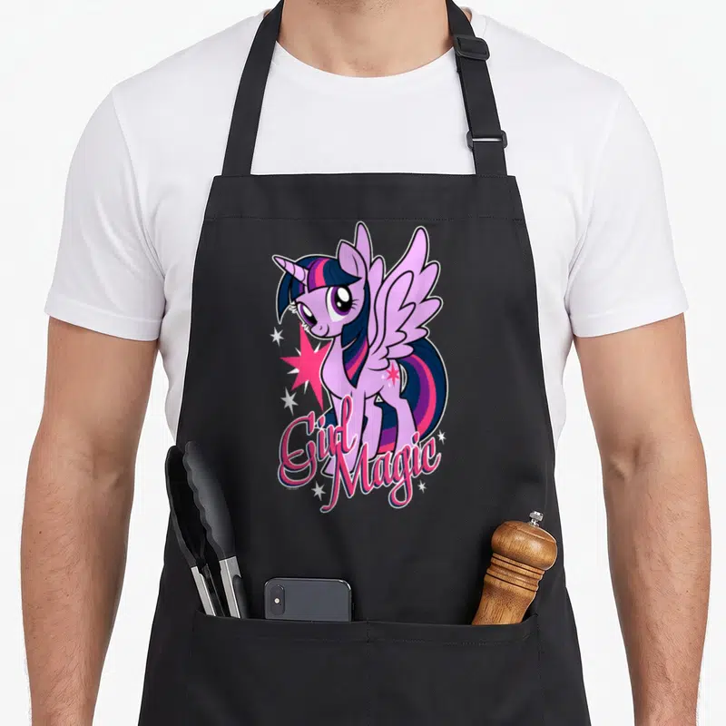 Tablier de cuisine noir avec illustration de licorne rose et texte Girl Magic entouré d'étoiles.