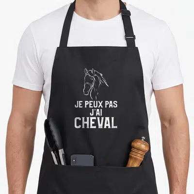 Tablier de cuisine noir avec une illustration de tête de cheval et le texte Je peux pas j'ai cheval en blanc.
