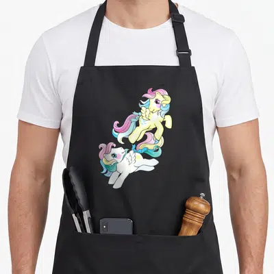 Tablier de cuisine noir avec deux poneys ailés aux crins multicolores flottant sur fond uni.