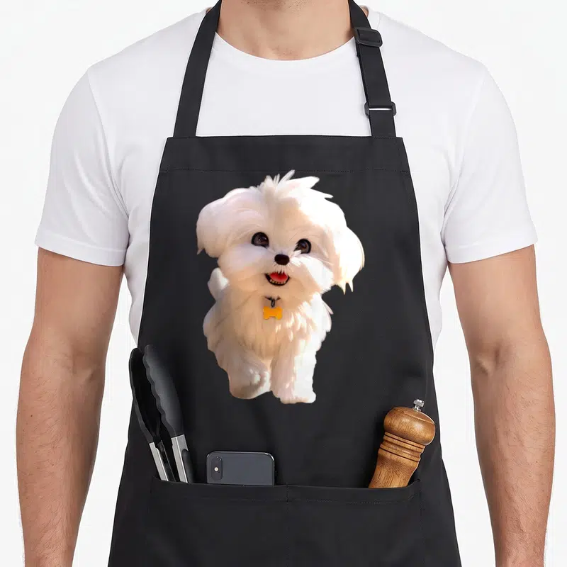 Tablier de cuisine noir avec un bichon maltais blanc souriant portant une étiquette os jaune sur son collier.