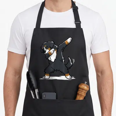 Tablier de cuisine noir avec illustration d'un Bouvier Bernois effectuant la danse dab sur fond uni.