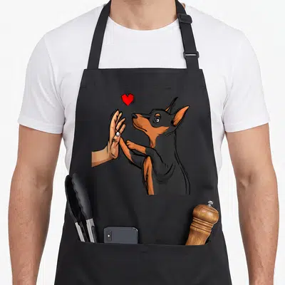 Tablier de cuisine noir avec illustration d'un faisant une haute main sous un cœur rouge.