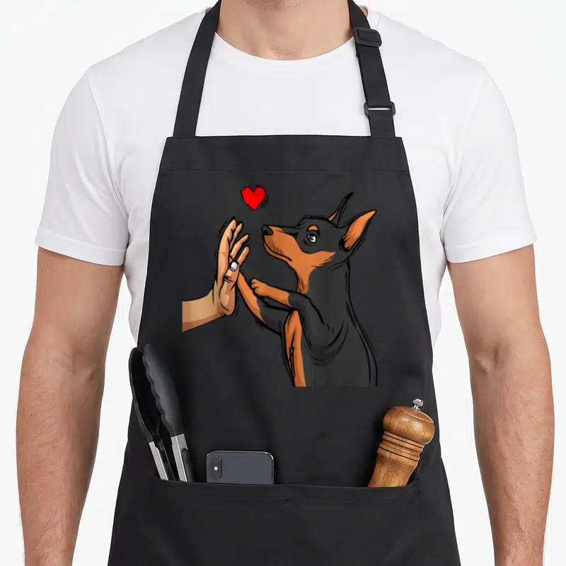 Tablier de cuisine noir avec illustration d'un faisant une haute main sous un cœur rouge.