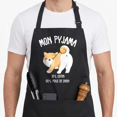 Tablier de cuisine noir avec illustration d'un Shiba Inu et texte blanc humoristique sur fond uni.