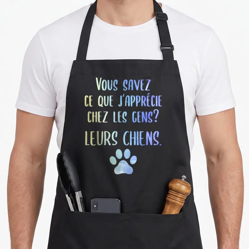 Tablier de cuisine noir avec texte coloré et une empreinte de patte bleue en bas du motif imprimé.