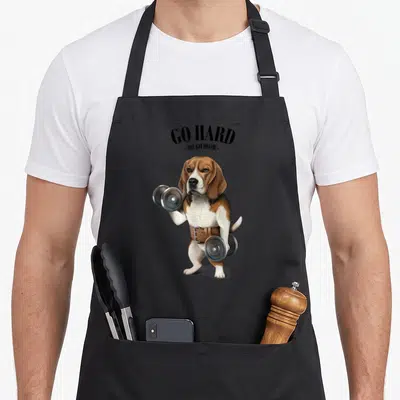 Tablier de cuisine noir avec illustration d'un beagle musclé tenant des haltères et portant une sangle de levage.