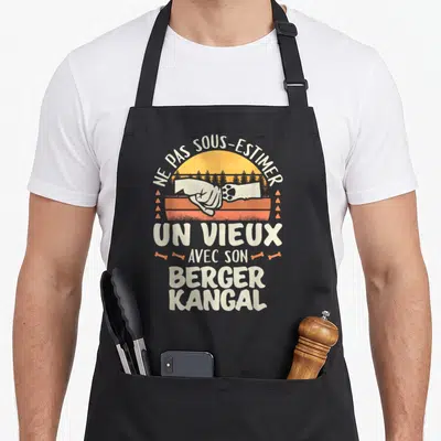Tablier de cuisine noir avec illustration vintage poing humain et patte de chien sur fond orange et forêt.