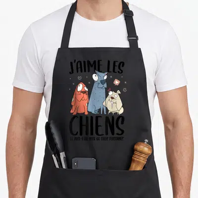 Tablier de cuisine noir avec trois chiens dessinés aux yeux écarquillés et le texte J'aime les chiens en gros caractères noirs.