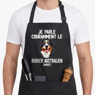 Tablier de cuisine noir avec tête de Berger Australien et texte blanc Je parle couramment le Berger Australien Wouf.