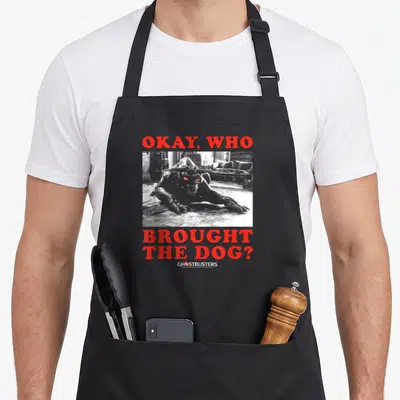 Tablier de cuisine noir avec une illustration en noir et blanc d'une créature aux yeux rouges et du texte rouge posant une question.