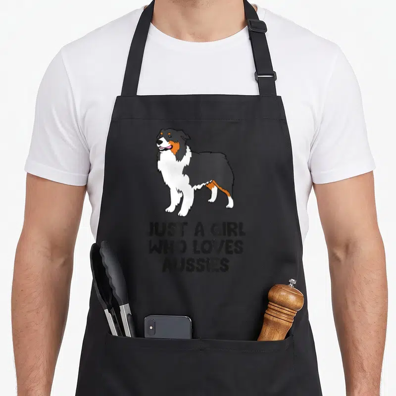 Tablier de cuisine noir avec illustration de berger australien et texte just a girl who loves aussies en bas.