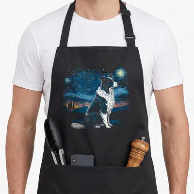 Tablier de cuisine noir avec illustration d'un Border Collie assis face à un ciel nocturne tourbillonnant aux étoiles jaunes et au village orange.