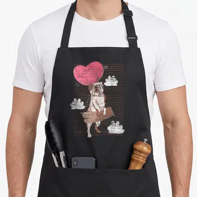 Tablier de cuisine noir avec illustration d'un bulldog anglais tenant un grand cœur rose en guise de ballon.