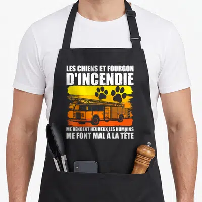 Tablier de cuisine noir avec inscription Les Chiens et Fourgon d'Incendie et silhouettes de patte de chien sur fond dégradé orange.