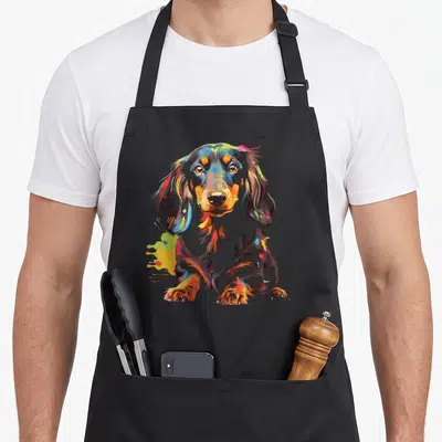 Tablier de cuisine noir avec illustration artistique d'un teckel chiot aux couleurs éclatantes et expressives.