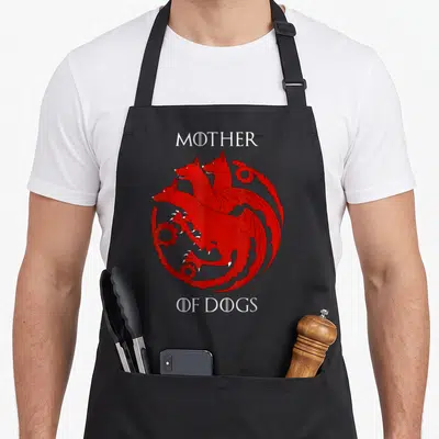 Tablier de cuisine noir avec un dragon rouge à trois têtes de chien et le texte Mother of Dogs imprimé en blanc.