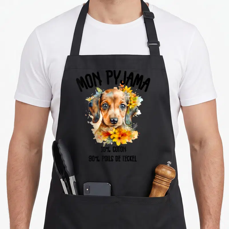 Tablier de cuisine noir avec illustration aquarelle d'un teckel entouré de fleurs et texte Mon Pyjama 90% Poils de Teckel.