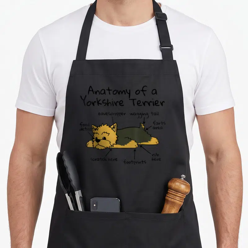 Tablier de cuisine noir avec illustration d'un Yorkshire Terrier et annotations humoristiques en anglais.