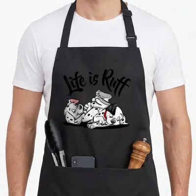 Tablier de cuisine noir avec deux chiots dalmatiens blancs à taches noires s'amusant ensemble sous la phrase Life is Ruff en écriture manuscrite noire.