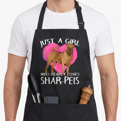Tablier de cuisine noir avec illustration d'un Shar-Pei devant un cœur rose et texte blanc en anglais.