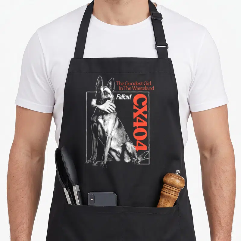 Tablier de cuisine noir avec illustration d'un chien, une main blanche et les textes The Goodest Girl In The Wasteland et CX404 en rouge.