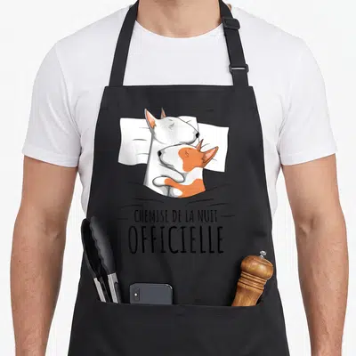 Tablier de cuisine noir avec illustration d'un Bull Terrier blanc et tache orange dormant sous une couverture.