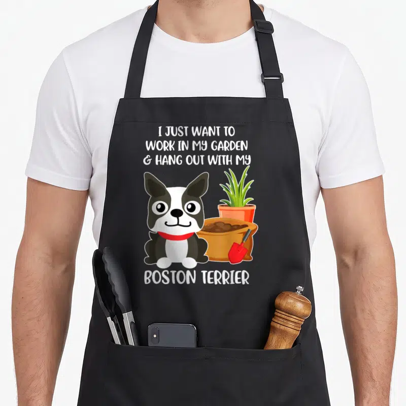 Tablier de cuisine noir avec illustration d'un Boston Terrier, un pot de fleurs et une pelle à côté du texte blanc.