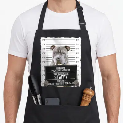 Tablier de cuisine noir avec illustration d'un chien gris posant devant un panneau de police.