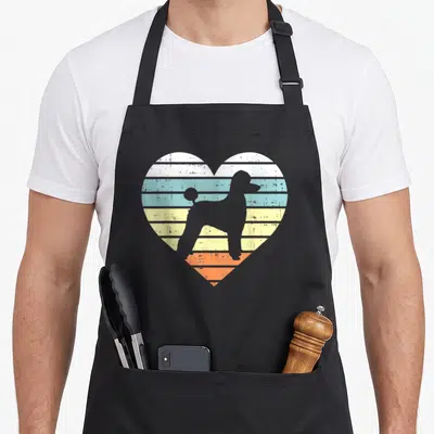 Tablier de cuisine noir avec un cœur aux couleurs pastel contenant la silhouette d'un caniche en style rétro.