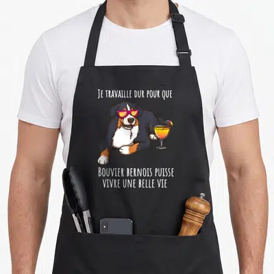 Tablier de cuisine noir avec illustration d'un Bouvier Bernois en lunettes de soleil tenant un verre coloré.