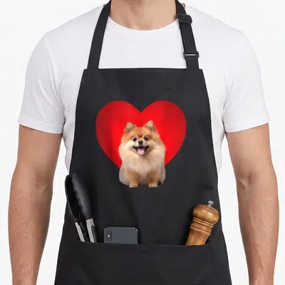 Tablier de cuisine noir avec un Pomeranian devant un grand Coeur rouge vif.