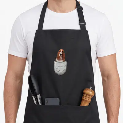 Tablier de cuisine noir avec illustration d'un Basset Hound dans un sac de poitrine gris.