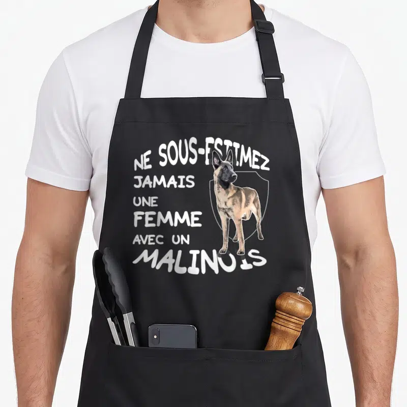 Tablier de cuisine noir avec l'inscription Ne sous-estimez jamais une femme avec un malinois et un chien illustré.
