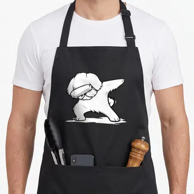 Tablier de cuisine noir avec un bichon maltais blanc effectuant une pose dab stylisée en dessin au trait noir.