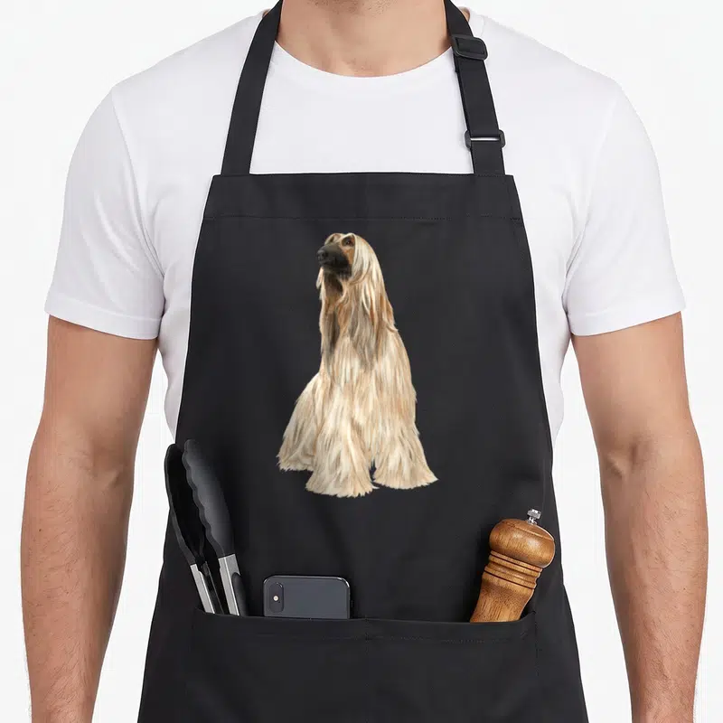 Tablier de cuisine noir avec illustration d'un Afghan Hound assis au long poil soyeux beige et noir.