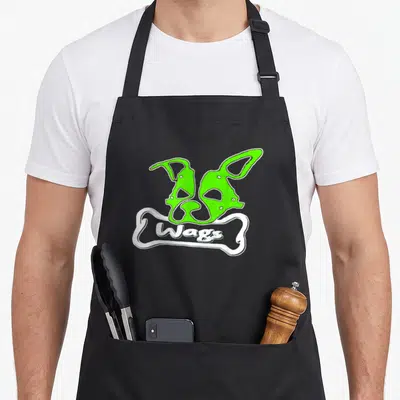 Tablier de cuisine noir avec deux masques verts au-dessus d'un os blanc portant linscription Wags