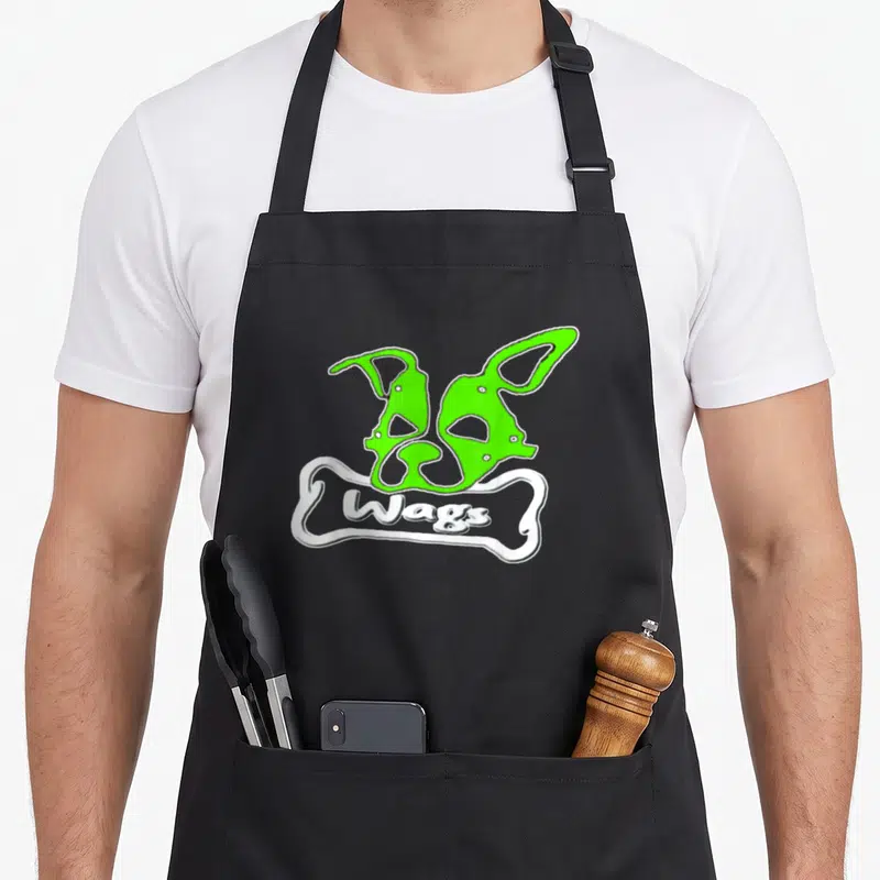 Tablier de cuisine noir avec deux masques verts au-dessus d'un os blanc portant l'inscription Wags