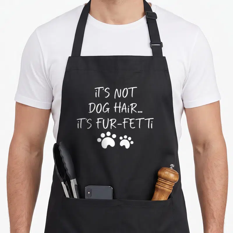 Tablier de cuisine noir avec inscription blanche It's Not Dog Hair It's Fur-Fetti et deux traces de pattes en dessous.