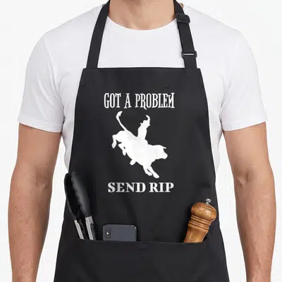 Tablier de cuisine noir avec inscription « Got A Problem Send Rip » et silhouette blanche d'un cavalier de rodeo.